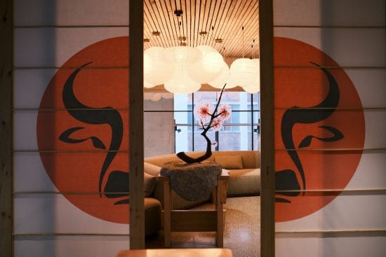 A stylish interior featuring Japanese-inspired wall art with black dragon motifs on a red background, complemented by soft lighting and contemporary furniture, creating a calming and elegant atmospher.