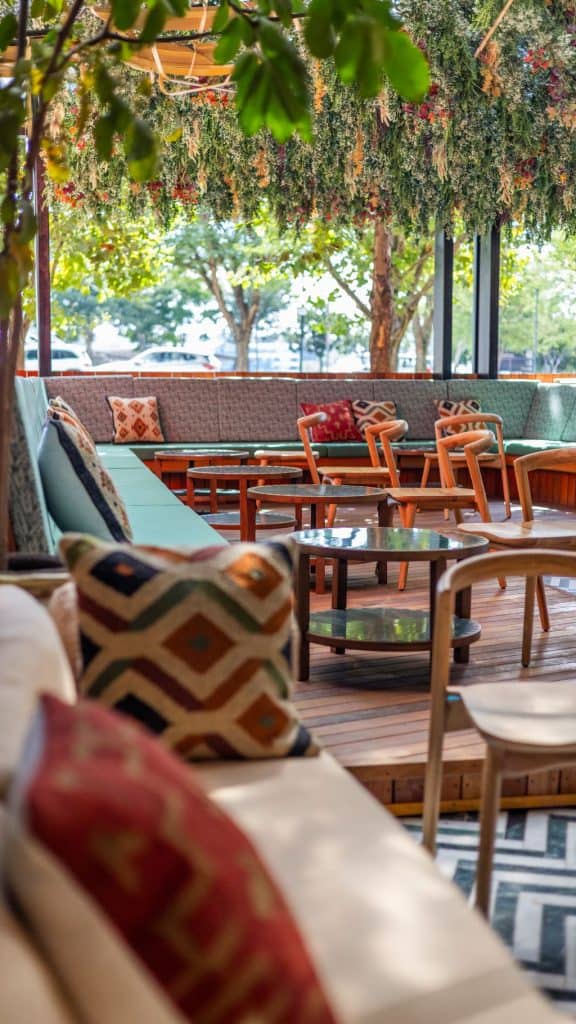 Stylish outdoor lounge area at Menlyn with comfortable seating, colourful cushions, and lush greenery, perfect for relaxing and socialising.