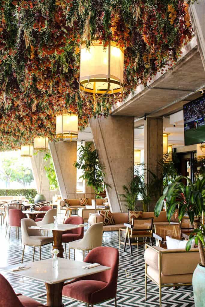 Elegant restaurant interior with lush hanging floral arrangements, modern lighting, and stylish seating for a luxurious dining experience.