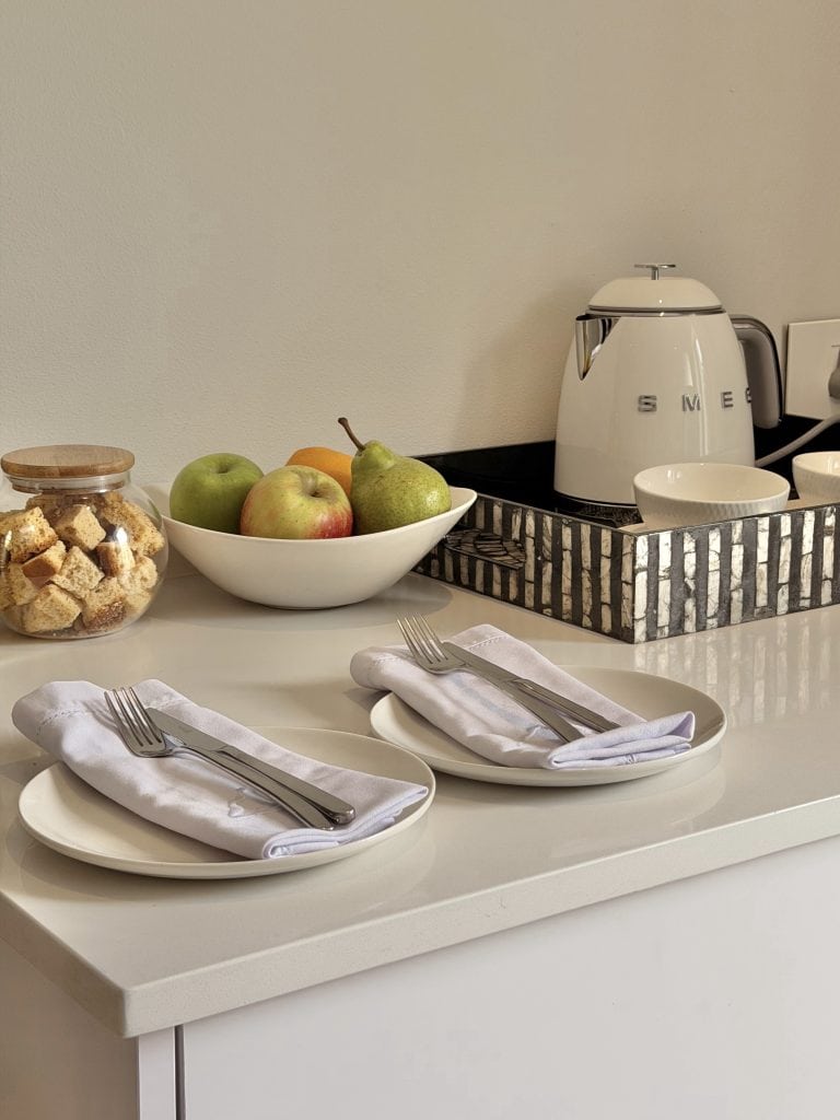 Modern kitchen countertop with apples, cereal, and a white kettle, ready for breakfast.